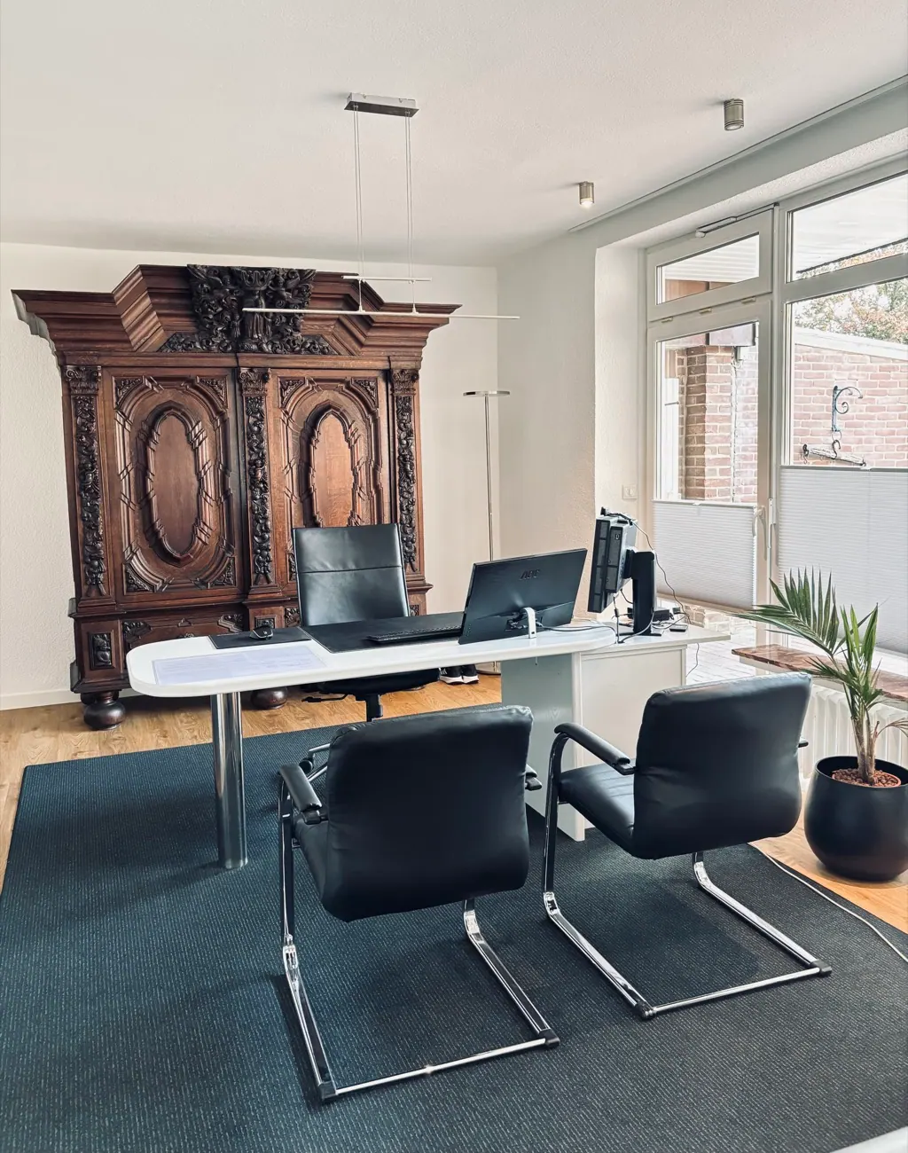 Sprechzimmer mit Schreibtisch und Besucherstühlen